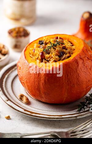 Tasty baked pumpkin stuffed with rice, vegetables, cashews and dried fruits on white background Stock Photo