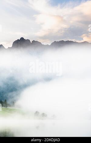 Herbststimmung an einem kleinen See in den bayerischen Alpen, im Hintergrund das Karwendelgebirge, eine kleine Halbinsel im Nebel und die Spiegelung im Wasser. Die neblige Atmosphäre mit den zerklüfteten Bergen hat eine fast mystische Wirkung. Stockfoto