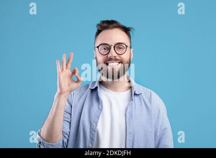 Alles ist okay. Portrait von glücklich kaukasischen Kerl zeigt OK Geste über blauen Studio-Hintergrund Stockfoto