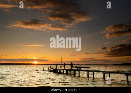 Hinterleuchtete Aufnahme bei Sonnenuntergang am Ammersee auf der TSV Fußgängerbrücke in Wartaweil. Stockfoto