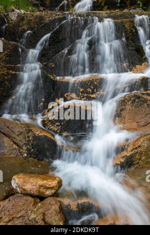 Die Quelle des Glasbaches unterhalb der Benediktenwand in der Jachenau, in den bayerischen Alpen. Bach mit Wasserfall. Stockfoto