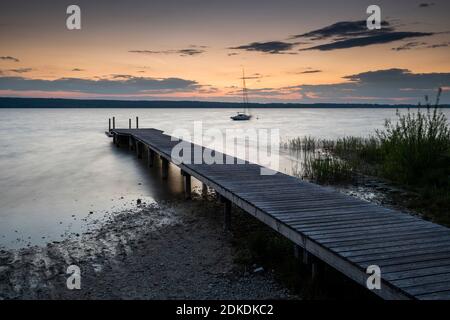 Wellen geglättet durch lange Belichtung auf einer Promenade am Ammersee, im Hintergrund der Sonnenuntergang. Stockfoto