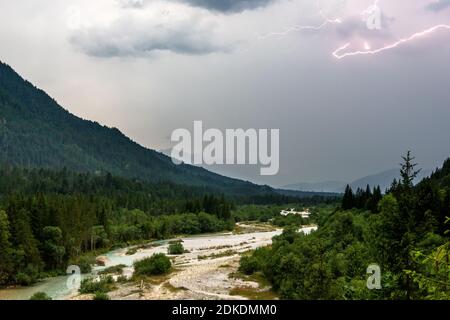 Gewitter über der Isar bei Wallgau, Blitzentladung und dunkle Wolken, im Hintergrund teilweise ein leichter Blick auf die Zugspitze und das Wettertsiegengebirge. Stockfoto