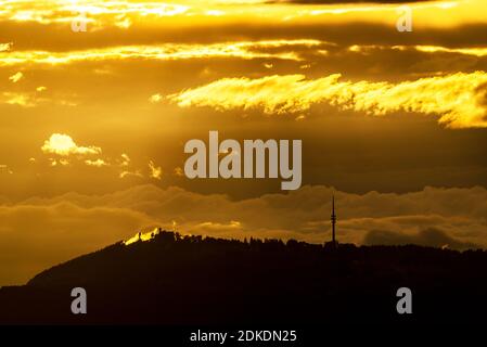 Goldenes Abendlicht mit Wolkenstimmung über dem Peißenberg bei Weilheim in den bayerischen Alpen. Stockfoto