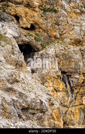 Augen und Mund im brüchigen Felsen am Brendlsteig im Karwendel, in den Alpen. Das Gesicht scheint die vorbeiziehenden Bergsteiger zu verspotten. Stockfoto