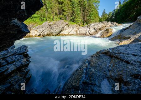 Schroffe Felsen am Rissbach in der Eng, beim Ahornboden bei Hinterriss. Klares Wasser fließt mit hoher Geschwindigkeit durch die Pools, im Hintergrund der Wald und blauer Himmel. HDR-Aufnahme Stockfoto