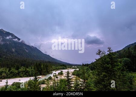 Gewitter über der Isar bei Wallgau, Blitzentladung und dunkle Wolken, im Hintergrund teilweise ein leichter Blick auf die Zugspitze und das Wettertsiegengebirge. Stockfoto