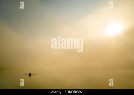 Kajakfahrer genießen eine Fahrt auf Sylvensteinspeicher am frühen Morgen bei Sonnenaufgang, bei Nebel und leichter Stimmung. Stockfoto