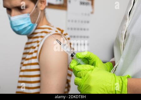 Der Mann erhält Jab, der Mann wird geimpft. Eltern bekommen einen Schuss Ärzte eingestellt, um erste zugelassene Dosen von Covid-19-Impfstoff zweite Generation zu geben Stockfoto