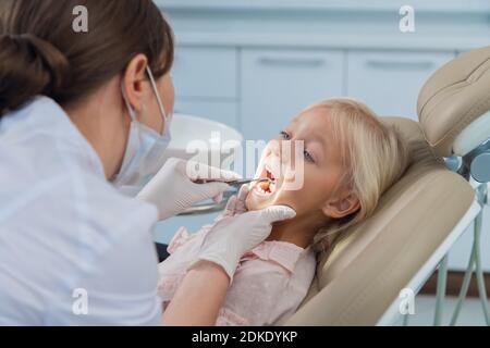 Eine kleine Patientin öffnet ihren Mund für eine zahnärztliche Untersuchung. Stockfoto