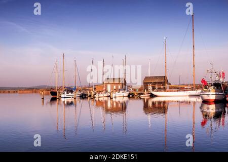 Boote und Schuppen im Hafen von Gager auf Rügen Spiegeln sich im Wasser bei Sonnenuntergang Stockfoto