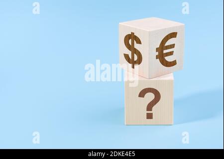 Wahl zwischen Dollar und Euro. Holzwürfel mit Euro- und Dollar-Symbolen an den Seiten über dem Würfel mit Fragezeichen. Euro oder Dollar c Stockfoto