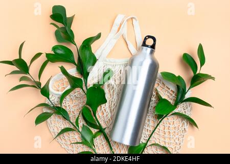 String bag with green leaves and metal bottle. Plastic free concept on yellow background. Stock Photo