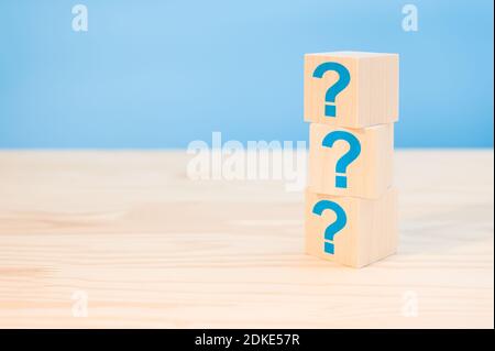 Würfel mit blauen Fragezeichen auf Holzhintergrund, Nahaufnahme. Leerzeichen für Text. Fragen Markieren Sie das Wort mit einem Holzwürfelblock auf dem Hintergrund des Tisches. FAQ-Frequenz Stockfoto