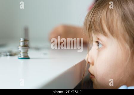 Portrait eines kleinen Mädchens, das am Tisch sitzt und Geld berechnet Stockfoto