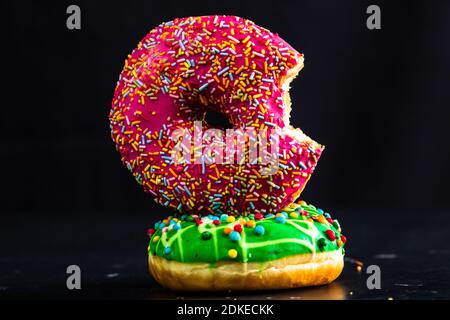 Gebissen rosa glasierten Donut mit Streuseln isoliert. Nahaufnahme von bunten Donuts. Stockfoto
