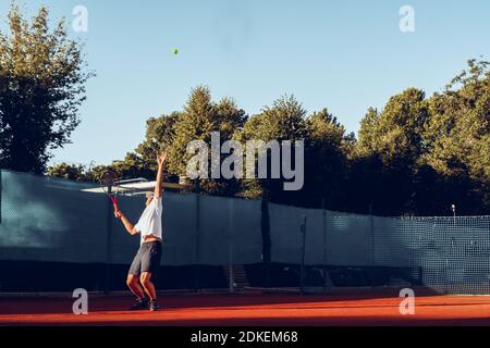 Junger professioneller Tennisspieler, der einen Service leistet Stockfoto