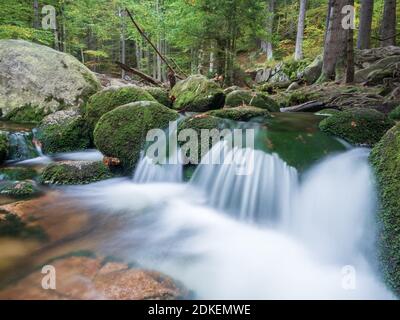 Blick auf die Schwelle des Flusses Szklarka in der Herbstlandschaft der Wälder des Riesengebirges. Lange Exposition von fließendem Wasser. Stockfoto