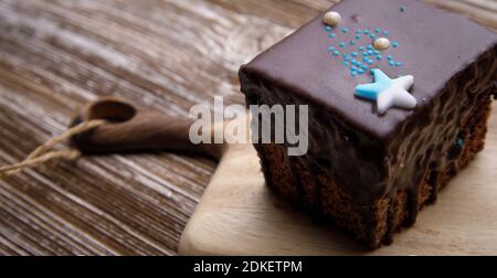 Hausgemachte Lebkuchen in Schokoladenglasur, verziert mit einem Zuckerstern auf einem Holzbrett. Selektiver Fokus. Stockfoto