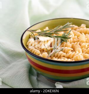 Gekochte Fusilli Pasta mit Rosmarin in einem Teller A auf einem hellen Tisch. Nahaufnahme, das Stillleben, selektiver Fokus. Stockfoto