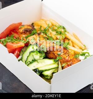 Fast Food Delivery. Griechische Souvlaki, Salat und Gyros Take-Away-Menü aus Fastfood-Restaurant serviert in recycelbaren Pappteller auf dem Tisch. Stockfoto