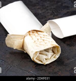 Traditionelles orientalisches Shawarma aus umweltfreundlicher Pappe. Oberfläche aus dunklem Stein. Konzept von Öko-Verpackungen von Wertstoffen. Stockfoto