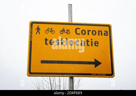 Richtungsschild zeigt den Weg zu einer Corona-Teststraße für Wanderer, Radfahrer und Mopeds. Übersetzung: Testlocatie bedeutet Teststandort. Stockfoto