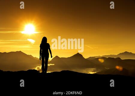 Frau schaut auf einen Sonnenaufgang in den Bergen Stockfoto