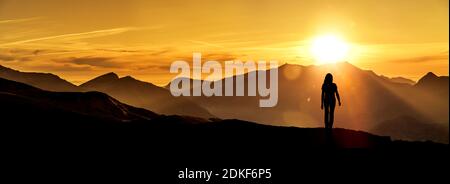 Frau schaut auf einen Sonnenaufgang in den Bergen Stockfoto