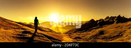 Frau schaut auf einen Sonnenaufgang in den Bergen Stockfoto