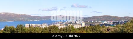 Panorama des Mumansker Seehafens auf einem sonnigen Sommer Homosexuell. Gebäude, Kräne, Frachtschiffe, нeavy Be- und Entladevorgänge. Blaues Meer, bewaldete Küste Stockfoto