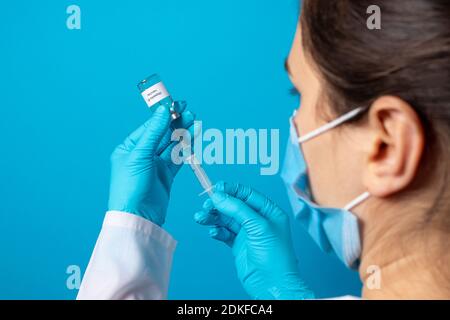 Ein Arzt oder Labortechniker hält ein Fläschchen mit einem Hepatitis-B-Impfstoff in der Hand. Mit einem Platz für Text auf blauem Hintergrund Stockfoto