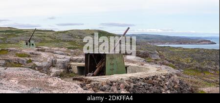 Die Überreste einer alten, verfallenden Flak-Batterie aus der Zeit des Zweiten Weltkriegs am steilen, felsigen Ufer der Barentssee jenseits des Bogens Stockfoto