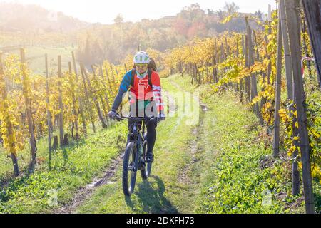 Ein Mann fährt im Herbst mit einem E-Bike (E-mtb) durch die Weinberge von Prosecco, Weinberge von Valdobbiadene, Provinz Treviso, Venetien, Italien Stockfoto