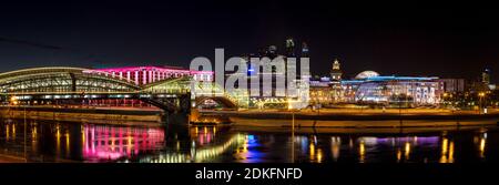 Nacht-Winterpanorama von der Moskwa-Ufer: Fußgängerbrücke Bogdan Khmelnitsky, Kiyevskaya Bahnhof, Stadt Moskau, Radisson Slavyans Stockfoto