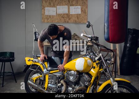 Ein starker Biker repariert sein Motorrad in der Garage. Der Innenraum der Werkstatt Stockfoto