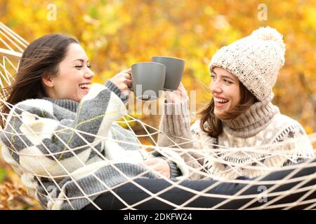 Zwei glückliche Freunde toasten mit Kaffeetassen im Herbsturlaub In einem Wald Stockfoto