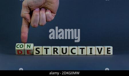 Destruktives oder konstruktives Symbol. Männliche Hand dreht Würfel und ändert das Wort "konstruktiv" zu "konstruktiv". Geschäftliches und konstruktives Konzept. Bea Stockfoto