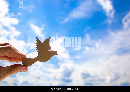 Mann Hand hält hölzernen Vogel auf Wolke Himmel Hintergrund. Die Entwicklung der Phantasie, kopieren Raum. Stockfoto