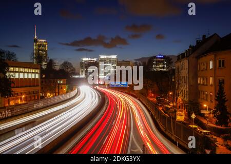 Essen, Ruhrgebiet, Nordrhein-Westfalen, Deutschland - Autobahn A40 im abendlichen Hauptverkehrsverkehr mit Blick in die Essener Innenstadt mit dem RWE-Turm, der Evonik-Zentrale und dem Postbank-Hochhaus. Stockfoto