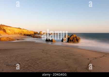 Atemberaubende lange Belichtung auf glatte Wellen in Felsformationen bei Sonnenuntergang, Sequit Punkt, Leo Carillo State Beach, Malibu, Kalifornien Stockfoto