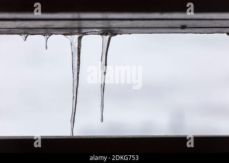 Eiszapfen, die an einem Holzgeländer hängen Stockfoto