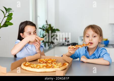 Zwei glückliche kleine Mädchen Freundinnen essen Pizza Scheiben. Stockfoto