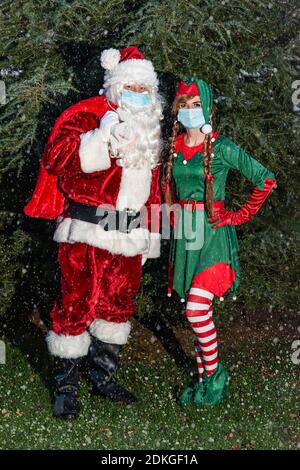 UK, Quorn - November 2020: Weihnachtsmann und ein Elf tragen in Gesichtsmasken, während sie unsere Geschenke zu liefern gehen, wie Schnee beginnt zu fallen Stockfoto