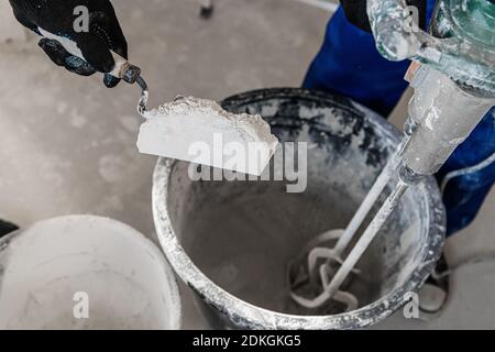 Der Vorarbeiter legt Zement in den Eimer. Er benutzt eine Kelle Stockfoto