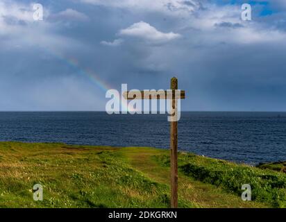 Am Horizont vor der Küste von Orkney bildet sich ein Regenbogen. Stockfoto