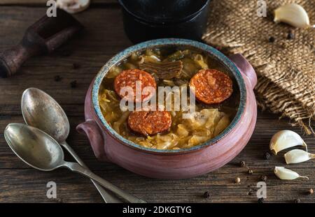 Weihnachts-Kohlsuppe in Keramikschale auf natürlichem Holzhintergrund. Stockfoto