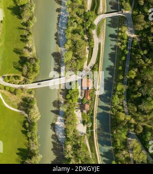 Draufsicht von einer Drohne an einem fahrenden Auto an einer Brücke über einen Fluss mit einem nebeligen Wald und einem Haus mit einem Parkplatz. Stockfoto