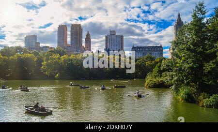 Ein schöner Tag im New Yorks Central Park, die Leute fahren vor beeindruckenden Skycrapers im Hintergrund. Stockfoto