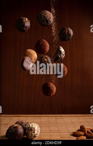 Handgemachte Schokoladentrüffel Bonbons fallen auf Holztisch Stockfoto